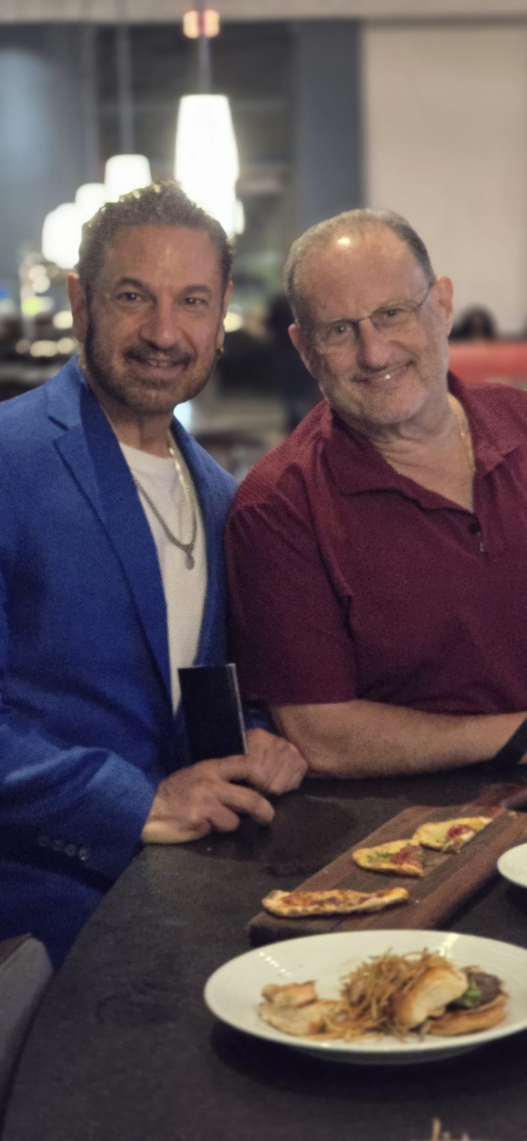 Two friends sharing a laugh over shared plates at a restaurant table