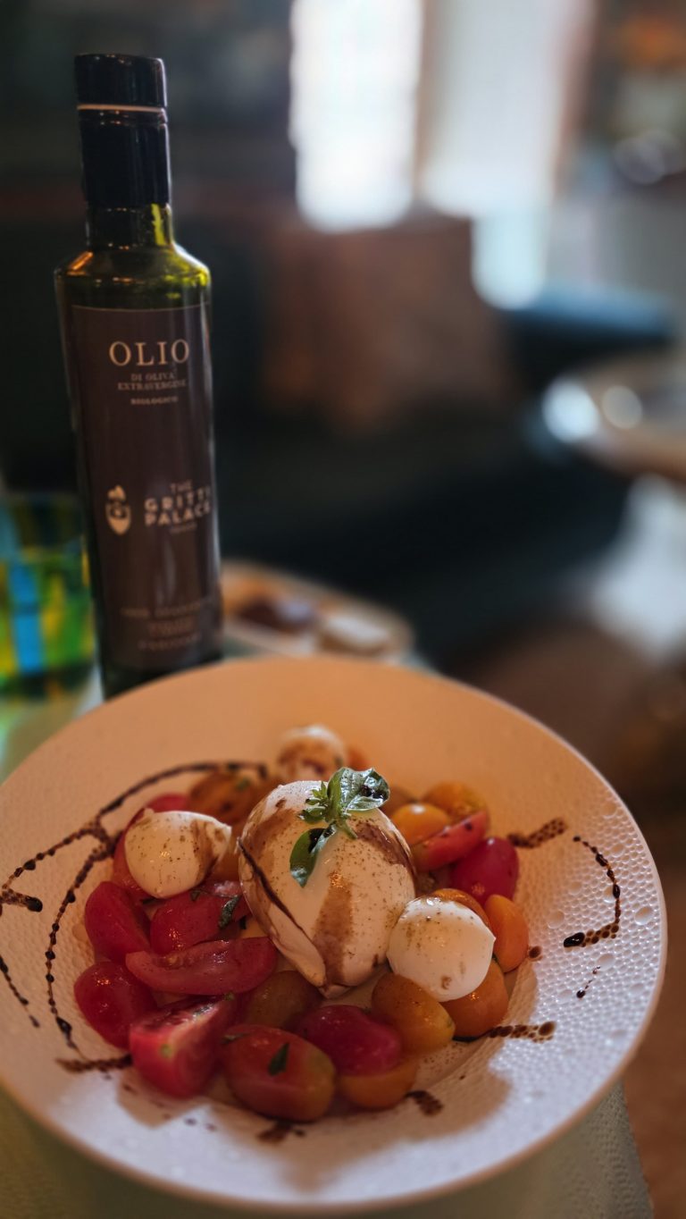 A dessert of strawberries and cream plated beside a bottle of Italian olive oil